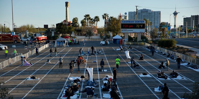 People prepare places to sleep at a makeshift camp for the homeless Monday, in Las Vegas.