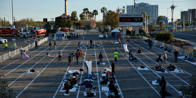 People prepare places to sleep at a makeshift camp for the homeless Monday, in Las Vegas.