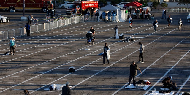 People prepare places to sleep in areas marked by painted boxes on the ground of a parking lot at a makeshift camp for the homeless Monday in Las Vegas.