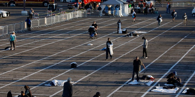 People prepare places to sleep in areas marked by painted boxes on the ground of a parking lot at a makeshift camp for the homeless Monday in Las Vegas.