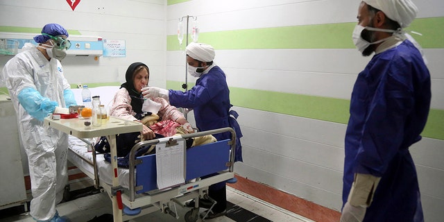 In this Saturday, March 7, 2020 file photo, a cleric, right, assists a medic treating a patient infected with the new coronavirus, at a hospital in Qom, about 80 miles (125 kilometers) south of the capital Tehran, Iran. Nine out of 10 cases of the virus in the Middle East come from the Islamic Republic. Fears remain that Iran may be underreporting its cases. Days of denials gave the virus time to spread as the country marked the 41st anniversary of its 1979 Islamic Revolution with mass demonstrations. For most people, the new coronavirus causes only mild or moderate symptoms. For some it can cause more severe illness.