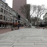 People walk through the nearly empty tourist area of Quincy Market in Boston, Mar. 11, 2020.
