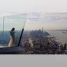 A person stands next to the skyline of lower Manhattan on the opening day of the Edge NYC, an outdoor observation deck on the 100th floor of 30 Hudson Yards in New York City, March 11, 2020. 