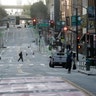 A man crosses a nearly empty street in San Francisco, Mar. 17, 2020. 