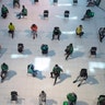 People practice social distancing as they sit on chairs spread apart in a waiting area for take-away food orders at a shopping mall in Bangkok, March 24, 2020. 