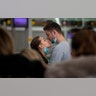 People remove their masks to kiss before a flight at the airport in Barcelona, Spain, March 12, 2020.