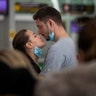 People remove their masks to kiss before a flight at the airport in Barcelona, Spain, March 12, 2020.