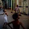 A boy smiles while playing baseball on the street with a friend in Havana, Cuba, March. 11, 2020. 