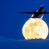 An aircraft passes the rising Super Worm Moon as it breaks through clouds in Frankfurt, Germany, March 9, 2020. 