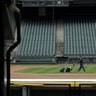 A grounds crew worker cuts the infield grass in front of empty seats around the time when the first pitch would have been thrown in the Mariners' Opening Day baseball game in Seattle, March 26, 2020. 