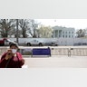 Washington, D.C.: A tourist wearing a face mask taking a picture standing on the empty pedestrian plaza outside the White House.