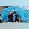 Workers exit a large tent set up in front of the emergency room at EvergreenHealth Medical Center in Kirkland, Wash., March 17, 2020.