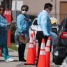 Health care staff from the Community Health of South Florida, Inc. (CHI) prepare to test people for the coronavirus in the parking lot of its Doris Ison Health Center in Miami, Fla., March 18, 2020.