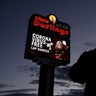 A man looks at a sign at a strip club advertising "coronavirus-free lap dances" Friday, March 13, 2020, in Las Vegas.