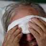 A 73-year-old man places a cold compress on his forehead while battling the flu at a hospital in Georgia. Doctors can test for the flu and get results within a day, but coronavirus testing as of March 2020 is still limited in the United States by availability.