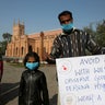 A Christian family holds a placard regarding the precautions for the newcoronavirus while they arrive to attend Sunday Mass at St. John's Cathedral in Peshawar, Pakistan, on March 15, 2020.