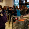 A woman wearing a face mask pushes a trolley as other customers wait in a queue to receive a card to allow them to shop at the supermarket in Athens, on March 16, 2020. Greek supermarkets are restricting the flow of customers entering the premises in another attempt to prevent the spread of coronavirus.