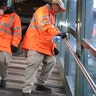 Employees of Metro-North Railroad disinfecting handrails at the New Rochelle Metro-North station.