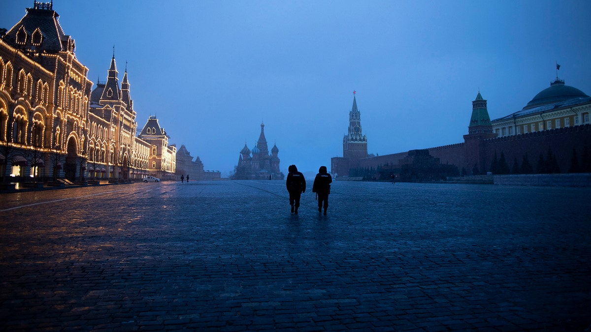 Two police officers patrol an almost empty Red Square, with St. Basil's Cathedral, center, and Spasskaya Tower and the Kremlin Wall, right, at the time when its usually very crowded in Moscow, Russia, Monday, March 30, 2020.