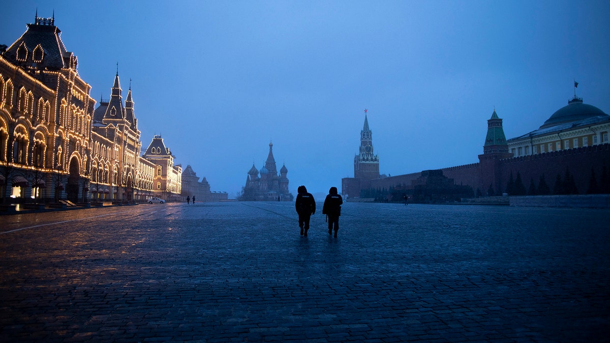 Two police officers patrol an almost empty Red Square, with St. Basil's Cathedral, center, and Spasskaya Tower and the Kremlin Wall, right, at the time when its usually very crowded in Moscow, Russia, Monday, March 30, 2020.