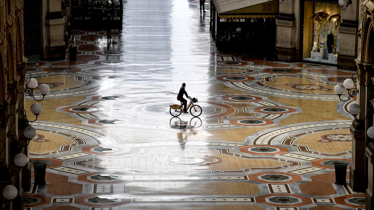 A cyclist rides along an empty Galleria Vittorio Emanuele II shopping arcade following Italy's lockdown due to the COVID-19 emergency, in Milan, Italy, Thursday, April 30, 2020. Italy is in its eighth week of national lockdown, with some partial easing of restrictions on everyday life slated to take effect on Monday, with lifting of yet more limits set for later in coming weeks, on condition the rate of contagion doesn’t sharply start rising again. (Claudio Furlan/LaPresse via AP)