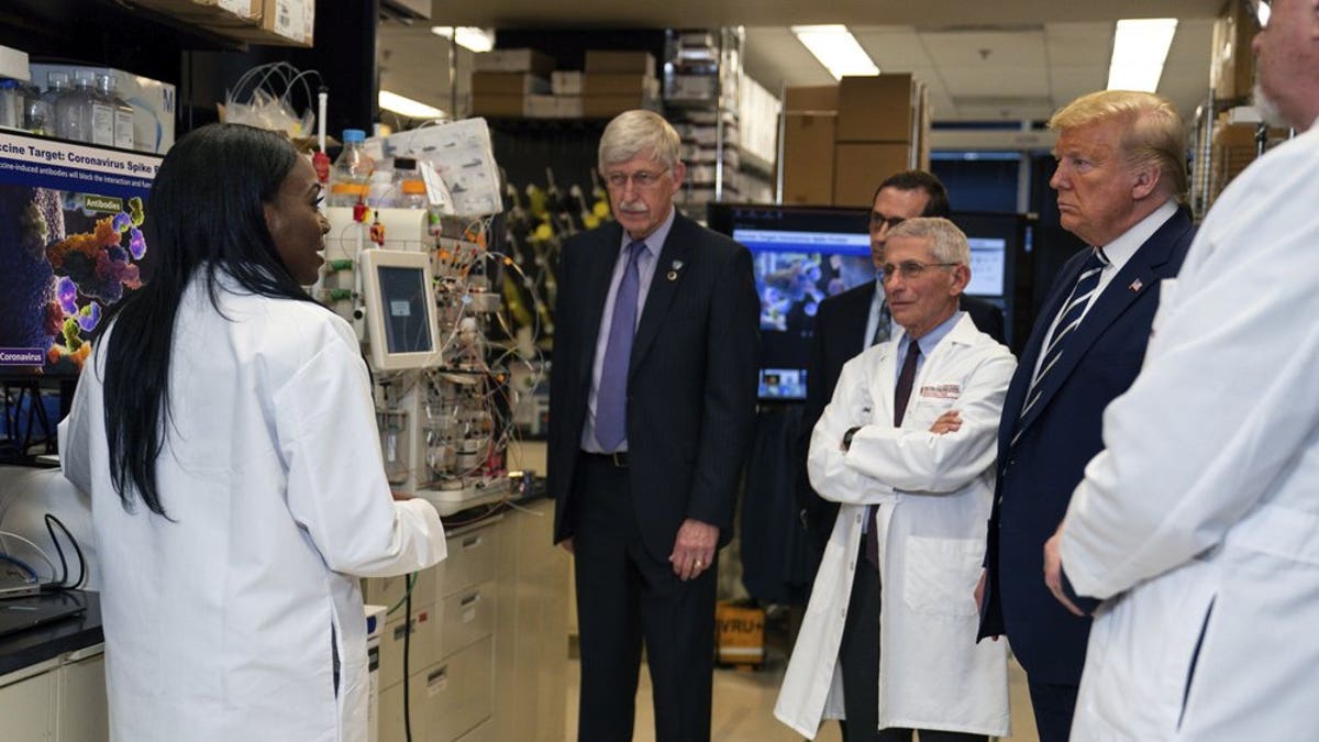 FILE - Dr. Kizzmekia Corbett, left, senior research fellow and scientific lead for coronavirus vaccines and immunopathogenesis team in the Viral Pathogenesis Laboratory, talks with President Donald Trump as he tours the Viral Pathogenesis Laboratory at the National Institutes of Health in Bethesda, Md., last month. (AP Photo/Evan Vucci)