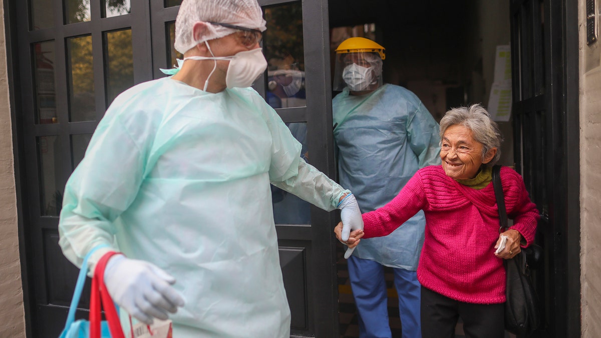 Medical staff evacuate an elderly woman from a nursing home after multiple residents of the facility tested positive for the new coronavirus, in Buenos Aires, Argentina, Wednesday, April 22, 2020. (AP Photo/Natacha Pisarenko)