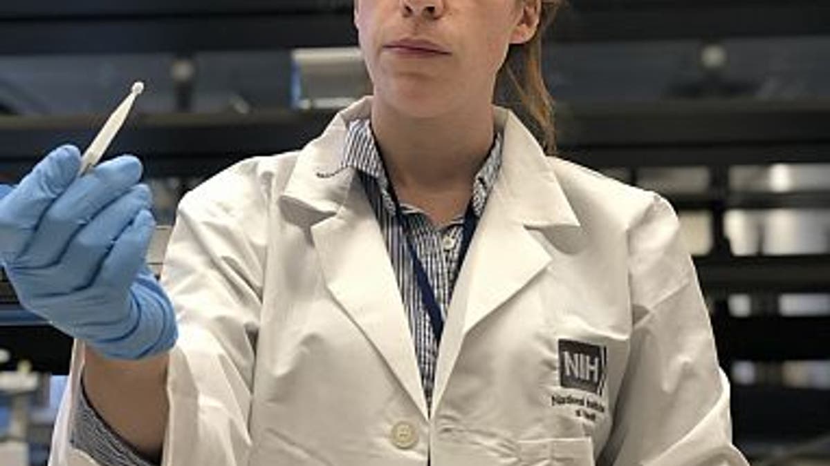 Kaitlyn Sadtler, Ph.D., study lead and principal investigator for laboratory testing, holds up a microsampling device from the home blood collection kit used in the study. (Credit: NIBIB)