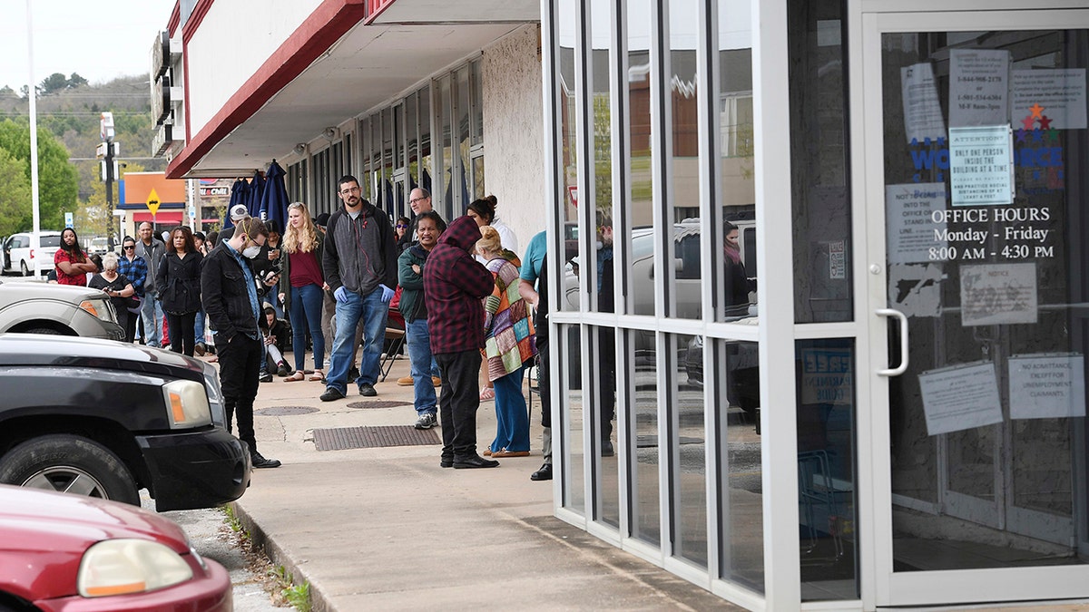 In this Monday, March 30, 2020, photo, a line of around 50 people extends from the door of Arkansas Workforce Center in Fayetteville, Ark. For information about small business loans and applying for Arkansas unemployment benefits go to www.arkansasedc.com/covid19. (JT Wampler/The Northwest Arkansas Democrat-Gazette via AP)