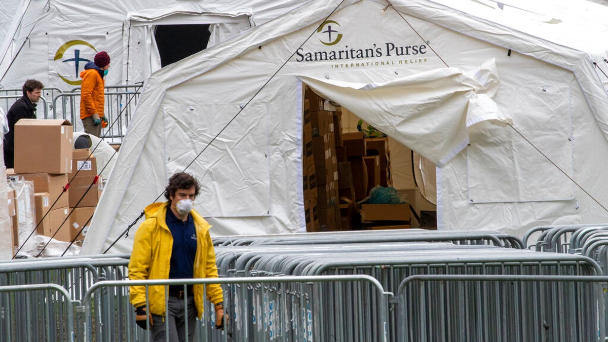 A Samaritan's Purse crew and medical personnel work on preparing to open a 68 bed emergency field hospital specially equipped with a respiratory unit in New York's Central Park, Tuesday, March 31, 2020, in New York. 