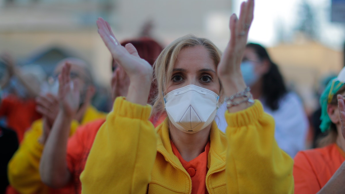 Health workers applaud as people react from their houses in support of the medical staff that are working on the COVID-19 virus outbreak at the Gregorio Maranon hospital in Madrid, Spain, Wednesday, April 1, 2020. The new coronavirus causes mild or moderate symptoms for most people, but for some, especially older adults and people with existing health problems, it can cause more severe illness or death. (AP Photo/Manu Fernandez)