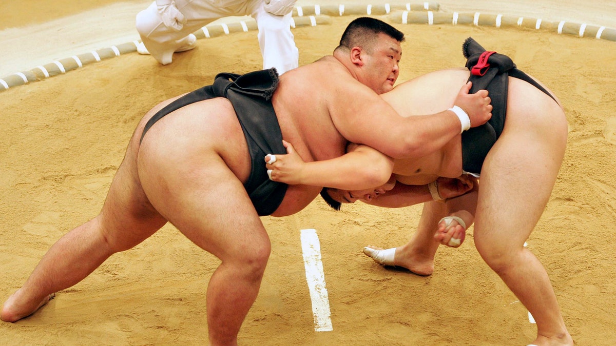 Sumo wrestler Takayuki Ichihara from Japan, left, fights against compatriot Keisho Shimoda in the heavyweight final of the Sumo tournament at the World Games in Duisburg, Germany in 2005. A Japanese sumo wrestler has tested positive for the coronavirus, further threatening postponement of next month’s Summer Grand Sumo Tournament which has already been delayed. (AP Photo/Martin Meissner, FIle)