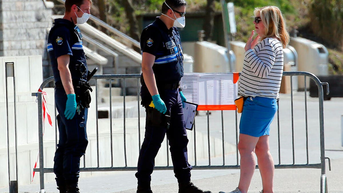Police officers speak to a woman during a nationwide confinement to prevent the spread of the coronavirus, in Biarritz, France, Saturday April 4, 2020. The new coronavirus causes mild or moderate symptoms for most people, but for some, especially older adults and people with existing health problems, it can cause more severe illness or death. (AP Photo/Bob Edme)