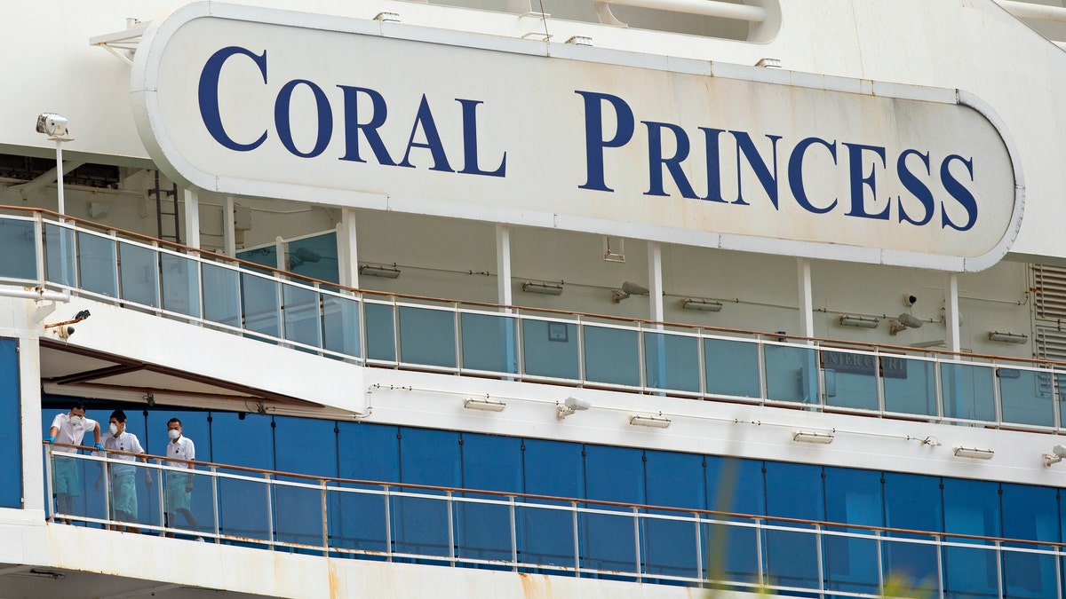 Coral Princess cruise crew members looks from their balcony at PortMiami as the coronavirus pandemic continues on April 5. (David Santiago/Miami Herald via AP)