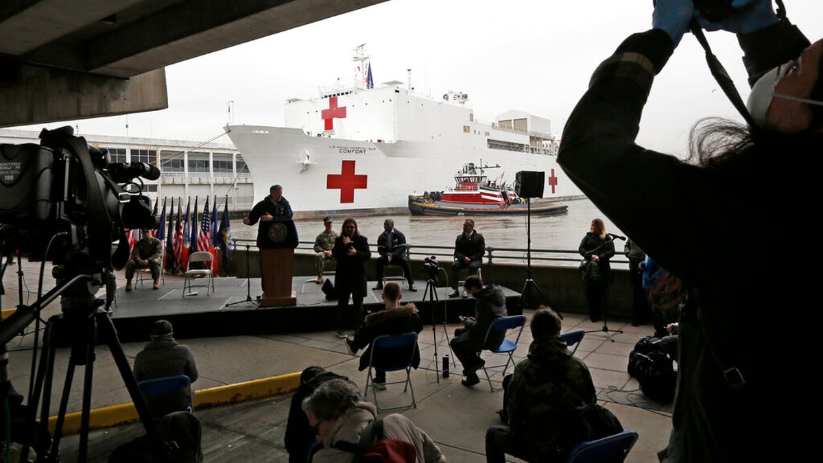 A journalist records speakers at a press briefing following the arrival of the USNS Comfort, a naval hospital ship with a 1,000 bed-capacity, March 30, 2020, at Pier 90 in New York. The ship will be used to treat patients who do not have the new coronavirus as land-based hospitals fill up to capacity with those that do.