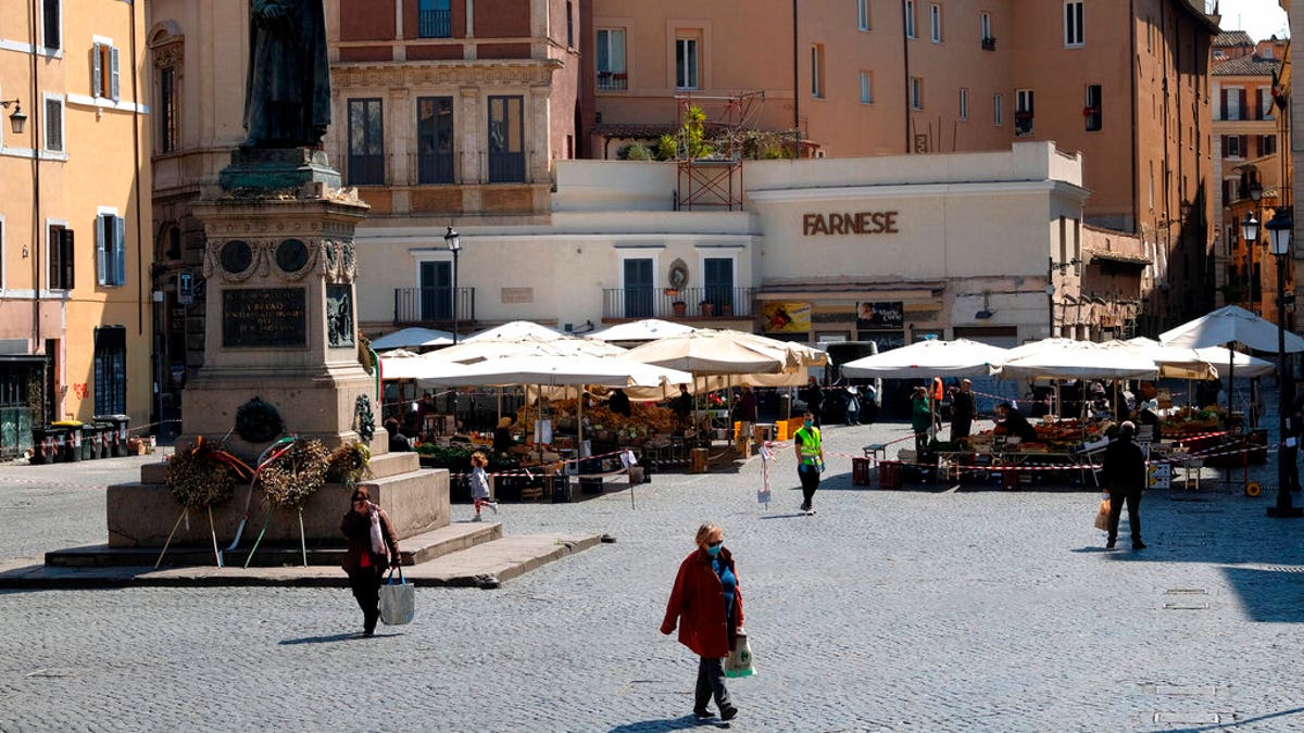 People shopping at Campo de Fiori fresh fruits and vegetables open market, as the statue of Giordano Bruno watches over the square, in Rome, Tuesday, April 7, 2020. 