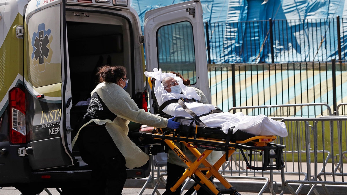 A patient is transferred from Elmhurst Hospital Center to a waiting ambulance during the current coronavirus outbreak, Tuesday, April 7, 2020, in New York. (AP Photo/Kathy Willens)