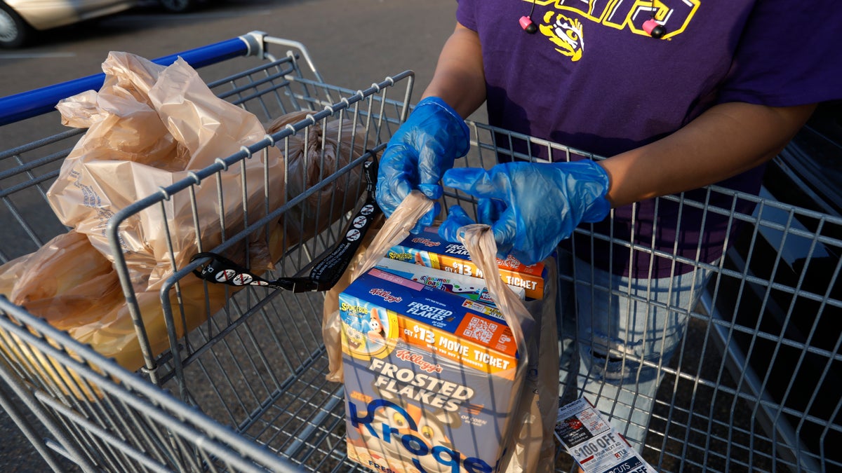 A gloved shopper prepares to load up her purchases in the Kroger parking lot in northeast Jackson, Miss., Wednesday, April 8, 2020. African Americans in Mississippi are being disproportionately affected by the new coronavirus, and many have underlying health problems that make them more vulnerable to it, the state epidemiologist said Tuesday. (AP Photo/Rogelio V. Solis)