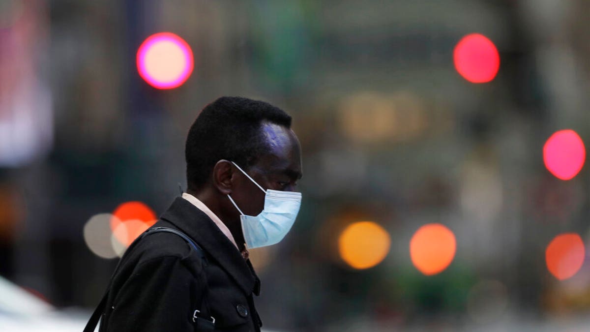 A man wearing a mask walks through New York's Times Square, Thursday, April 9, 2020, during the coronavirus epidemic. (AP Photo/Mark Lennihan)