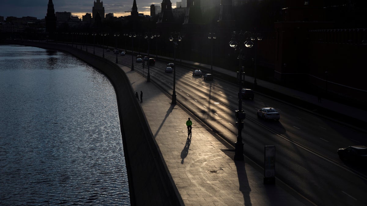A man rides a bike along the embankment of the Moskva River in front of the Kremlin in Moscow, Russia, Friday, April 10, 2020. 