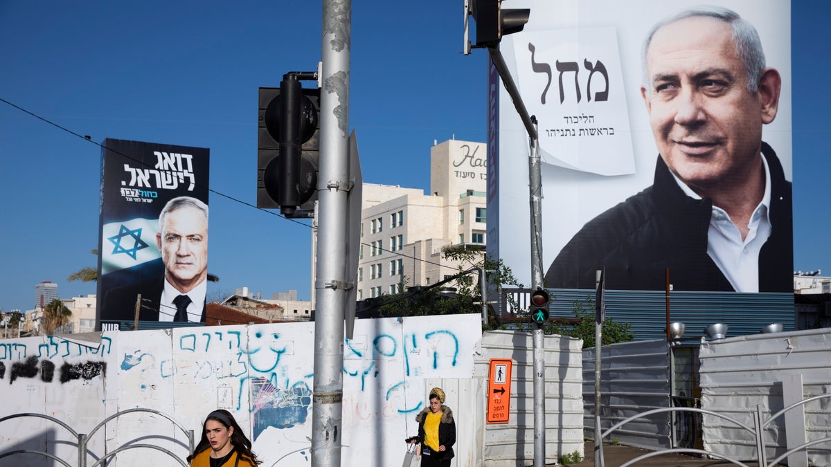 FILE: People walk next to election campaign billboards showing Israeli Prime Minister Benjamin Netanyahu, right, and Benny Gantz, left, in Bnei Brak, Israel. 