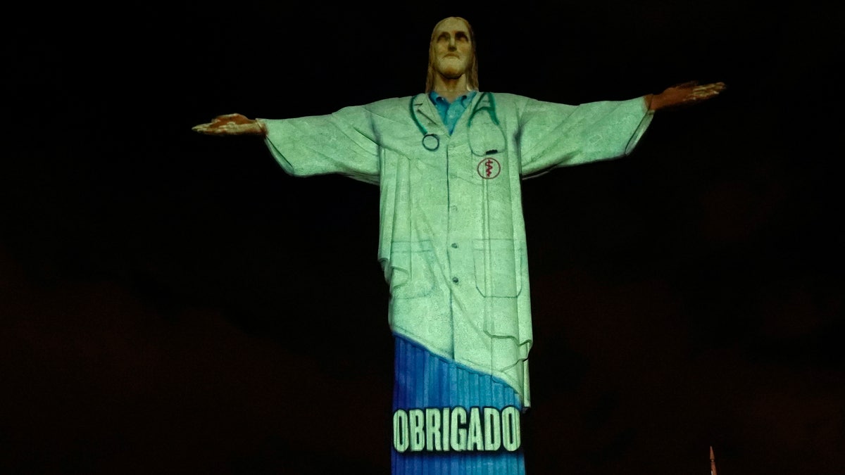 Rio's Christ the Redeemer statue is lit up in the likeness of a doctor and with the word "Thanks" projected in Portuguese, during an Easter service, in the midst of the new coronavirus pandemic, Rio de Janeiro, Brazil, Sunday, April 12, 2020. (AP Photo/Silvia Izquierdo)