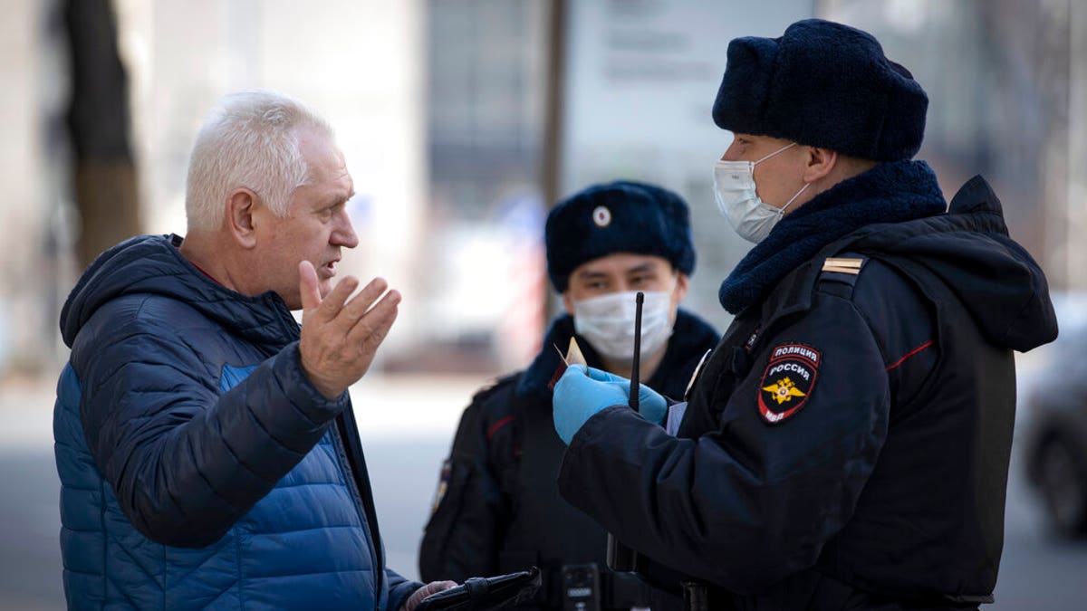 Russian police officers, wearing face masks to protect from coronavirus, check documents of a man to ensure a self-isolation regime due to coronavirus, in Moscow, Russia.