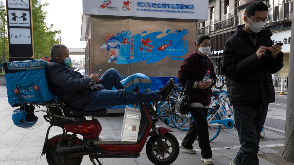 A delivery man wearing a mask against the coronavirus waits for orders in Wuhan in central China's Hubei province on Monday, April 13, 2020. 