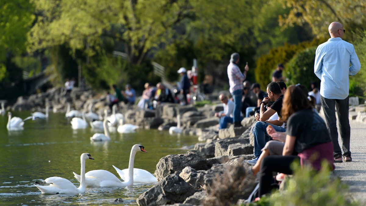 People enjoy the sun on the shore of Lake Biel during the state of emergency of the coronavirus disease (COVID-19) outbreak, in Biel, Switzerland, Monday, April 13, 2020. Countries around the world are taking increased measures to stem the widespread of the SARS-CoV-2 coronavirus, which causes the Covid-19 disease. (KEYSTONE/Anthony Anex)