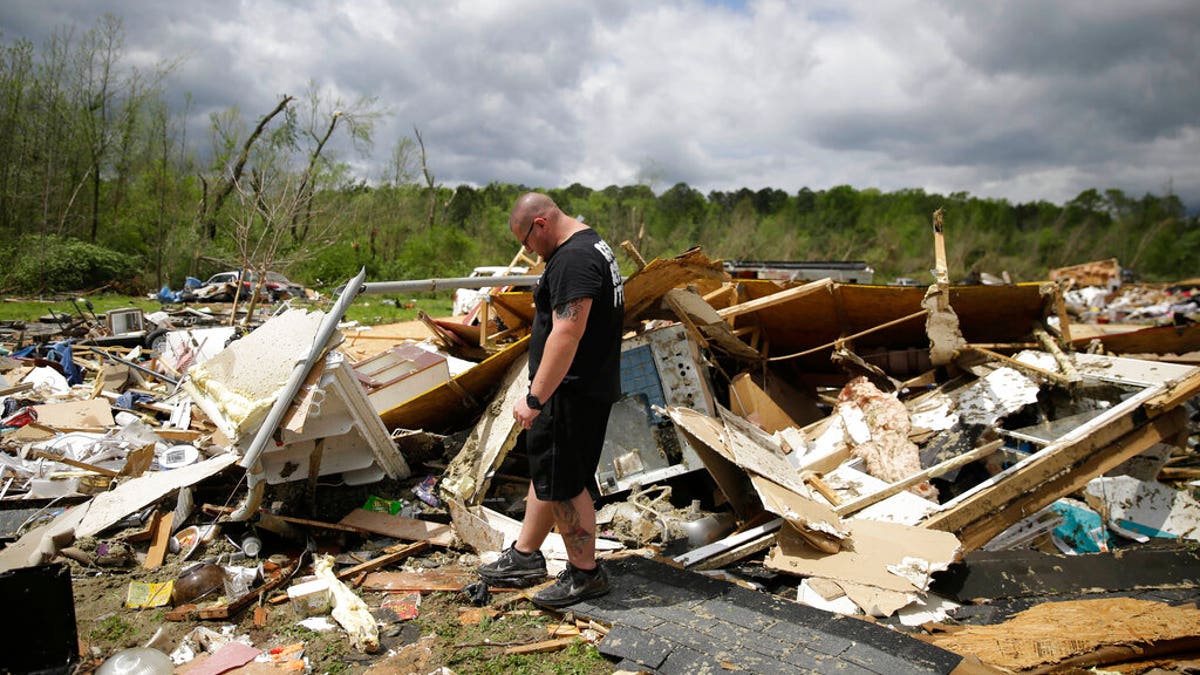 Aaron Pais kicking around debris at a mobile-home park wrecked by a tornado in Chatsworth, Georgia.