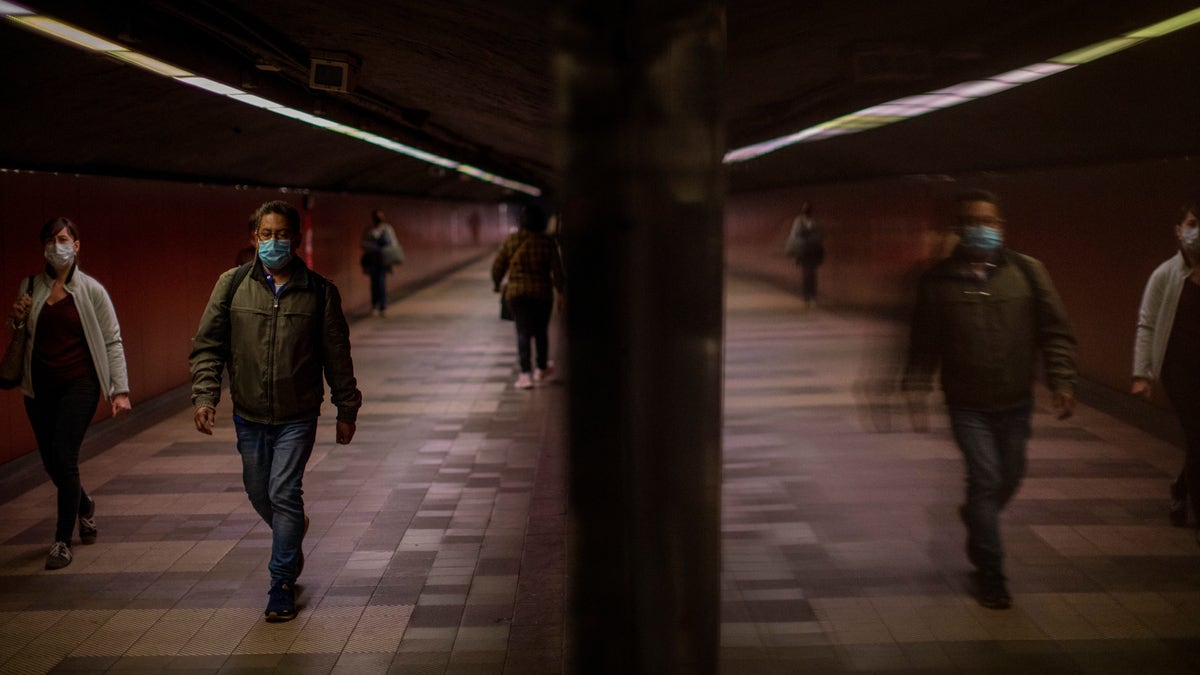 Passengers wearing face masks to prevent the spread of coronavirus, walk along a tunnel connecting platforms in a metro station in Barcelona, Spain, Wednesday, April 15, 2020. Spain has eased this week the conditions of Europe's strictest lockdown, allowing manufacturing, construction and other nonessential activity in an attempt to cushion the economic impact of the pandemic. (AP Photo/Emilio Morenatti)