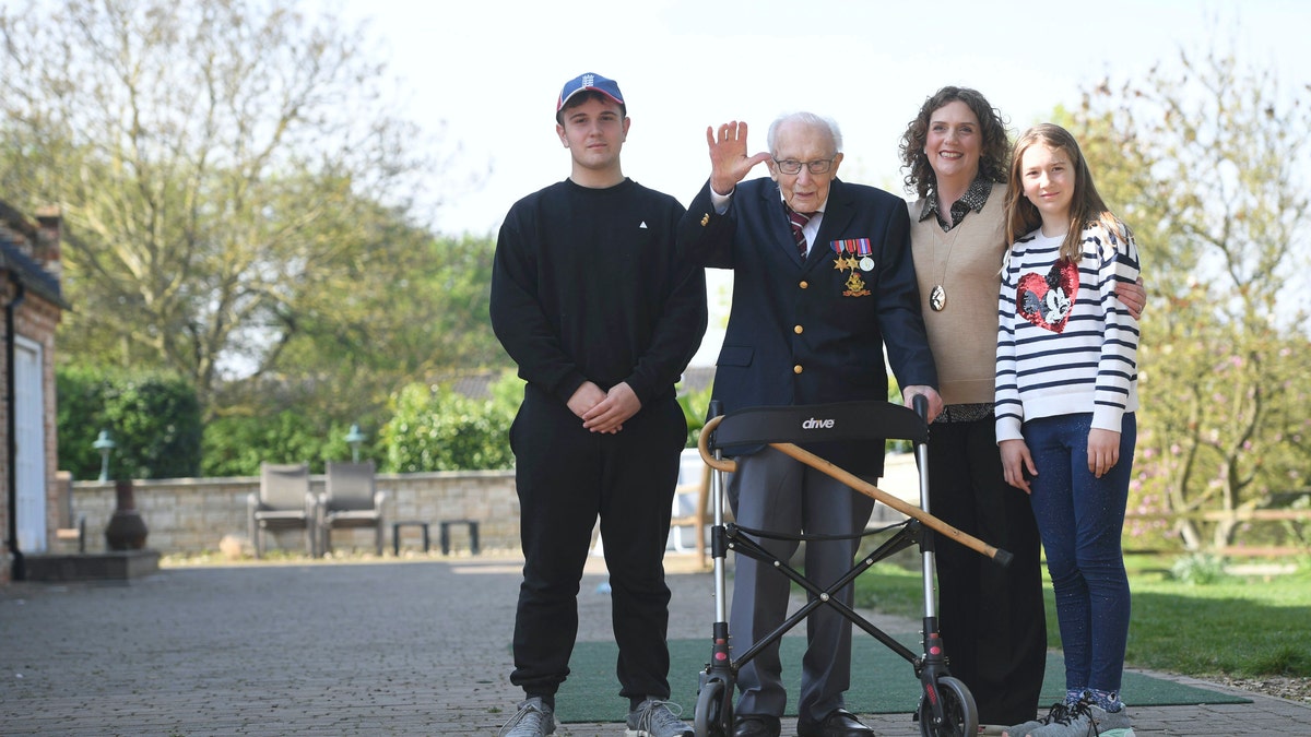 99-year-old war veteran Captain Tom Moore, with (left to right) grandson Benji, daughter Hannah Ingram-Moore and granddaughter Georgia, at his home in Marston Moretaine, Bedfordshire, after he achieved his goal of 100 laps of his garden - raising more than 12 million pounds for the NHS.  Joe Giddens/PA Wire via AP