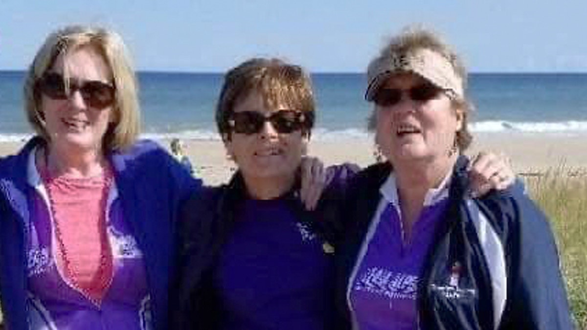 In this Sept. 2018 photo, Joanne Mellady, right, poses with her sisters Jean Sinofsky, left, and Joyce Smith, center, at a Massachusetts beach on Cape Cod during a bike trek fundraiser for Alpha 1.org. Mellady, who received a double lung transplant in 2007, died of the coronavirus in March 2020.