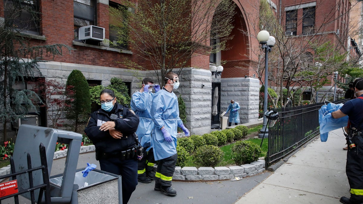 NYPD officers, FDNY firefighters, and emergency workers begin to discard and disrobe from their protective equipment after an emergency call at Cobble Hill Health Center Friday in the Brooklyn borough of New York. (AP Photo/John Minchillo)